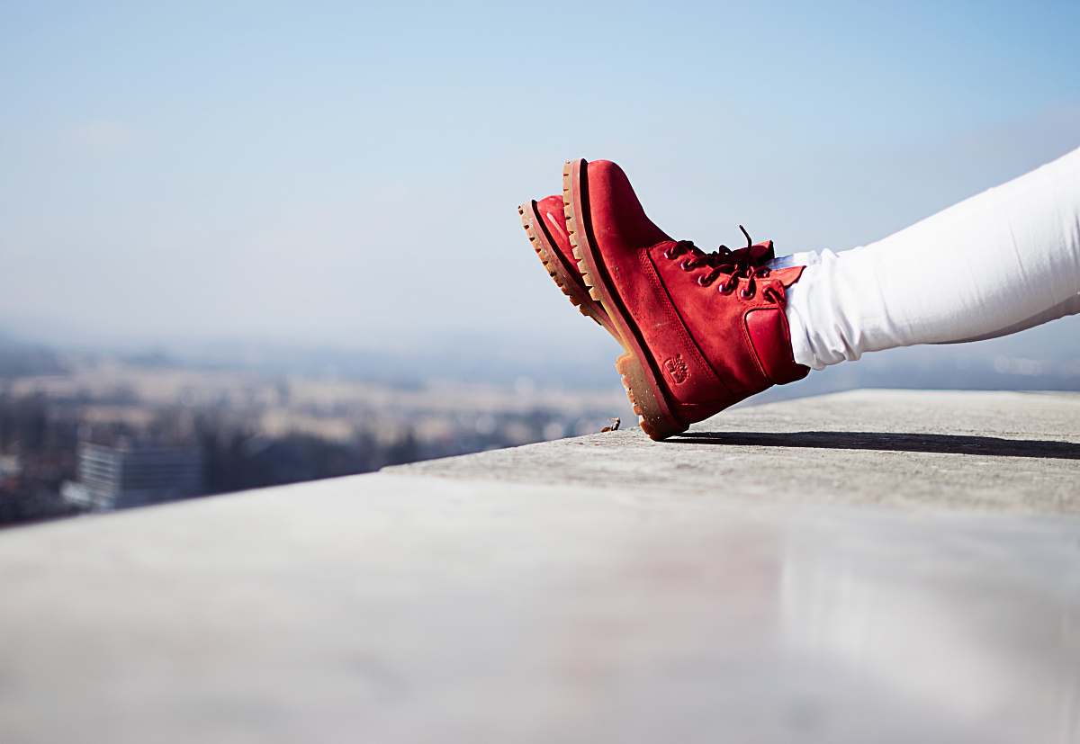 bled person wearing pair of red boots sitting on building top slovenia